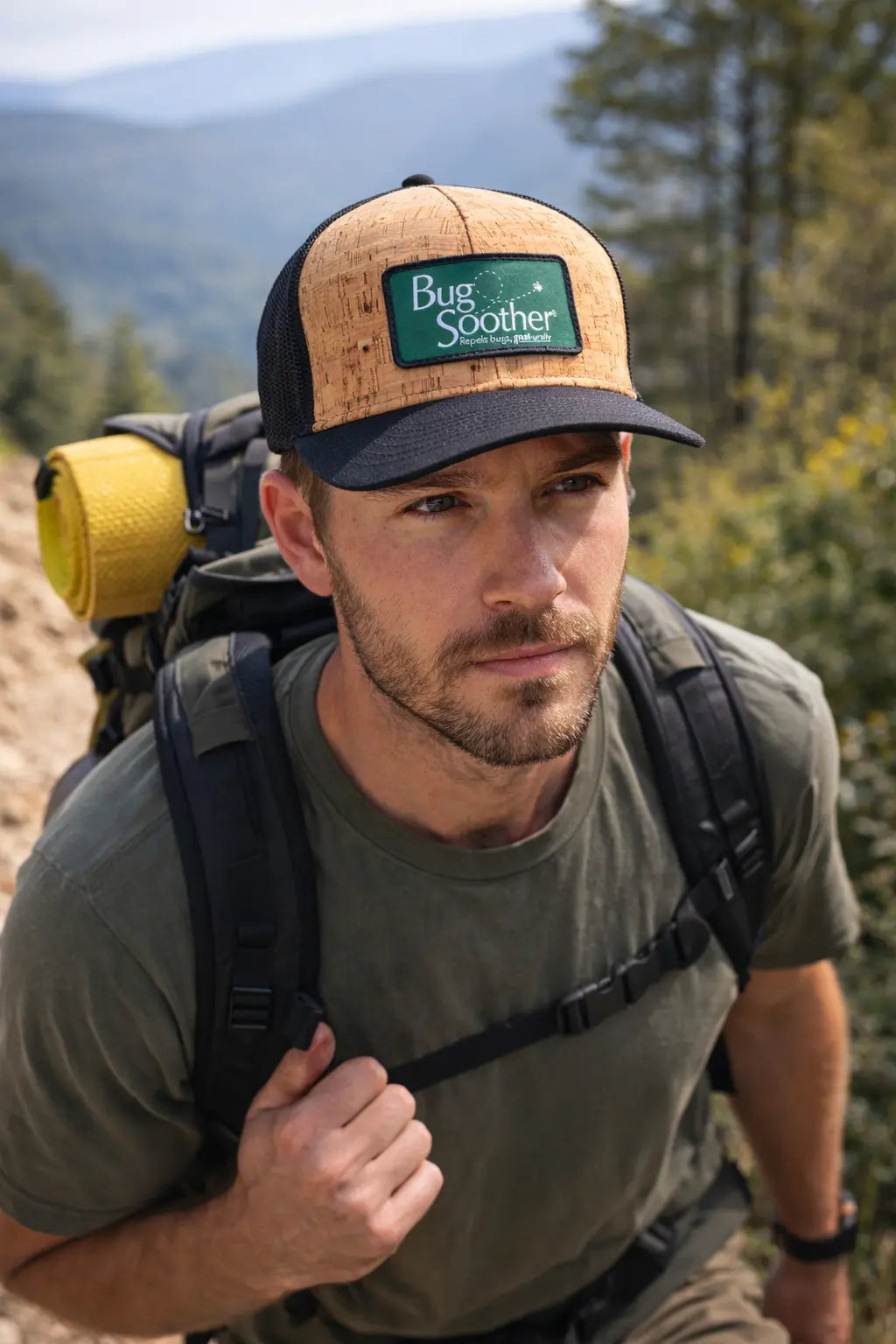 Man hiking with a backpack wearing a cap with 'Bug Soother' logo