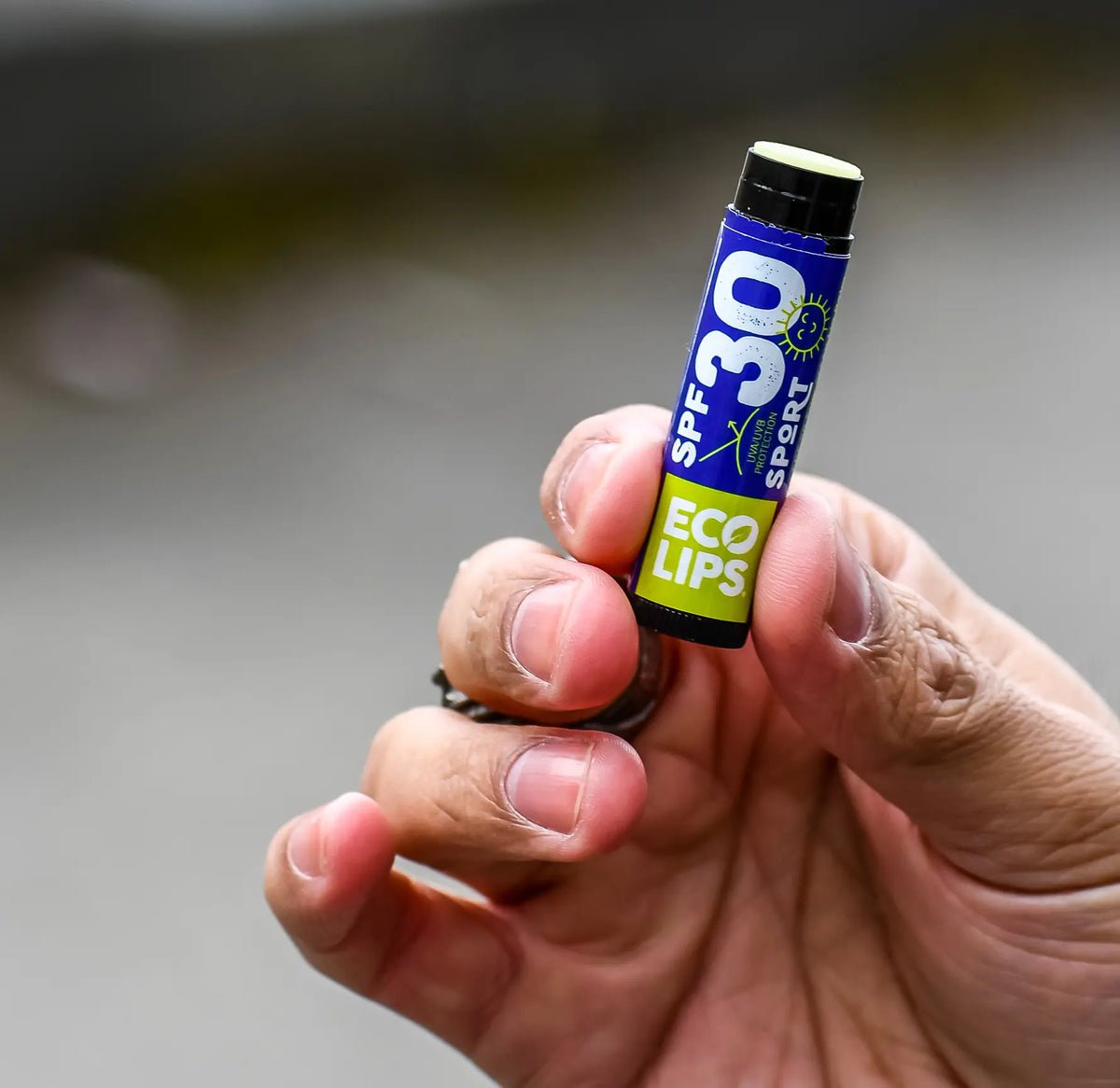 A man holding up an open SPF 30 lip balm. 