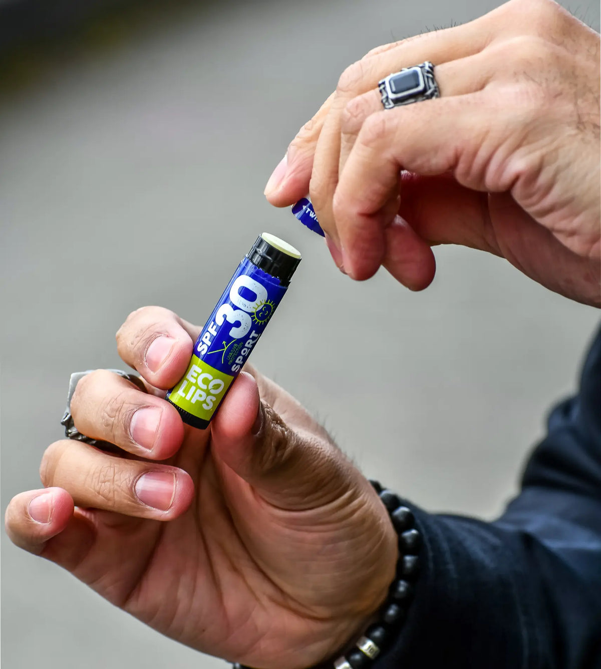 Hands holding an spf 30 lip balm getting ready to put the lid back on the balm. 
